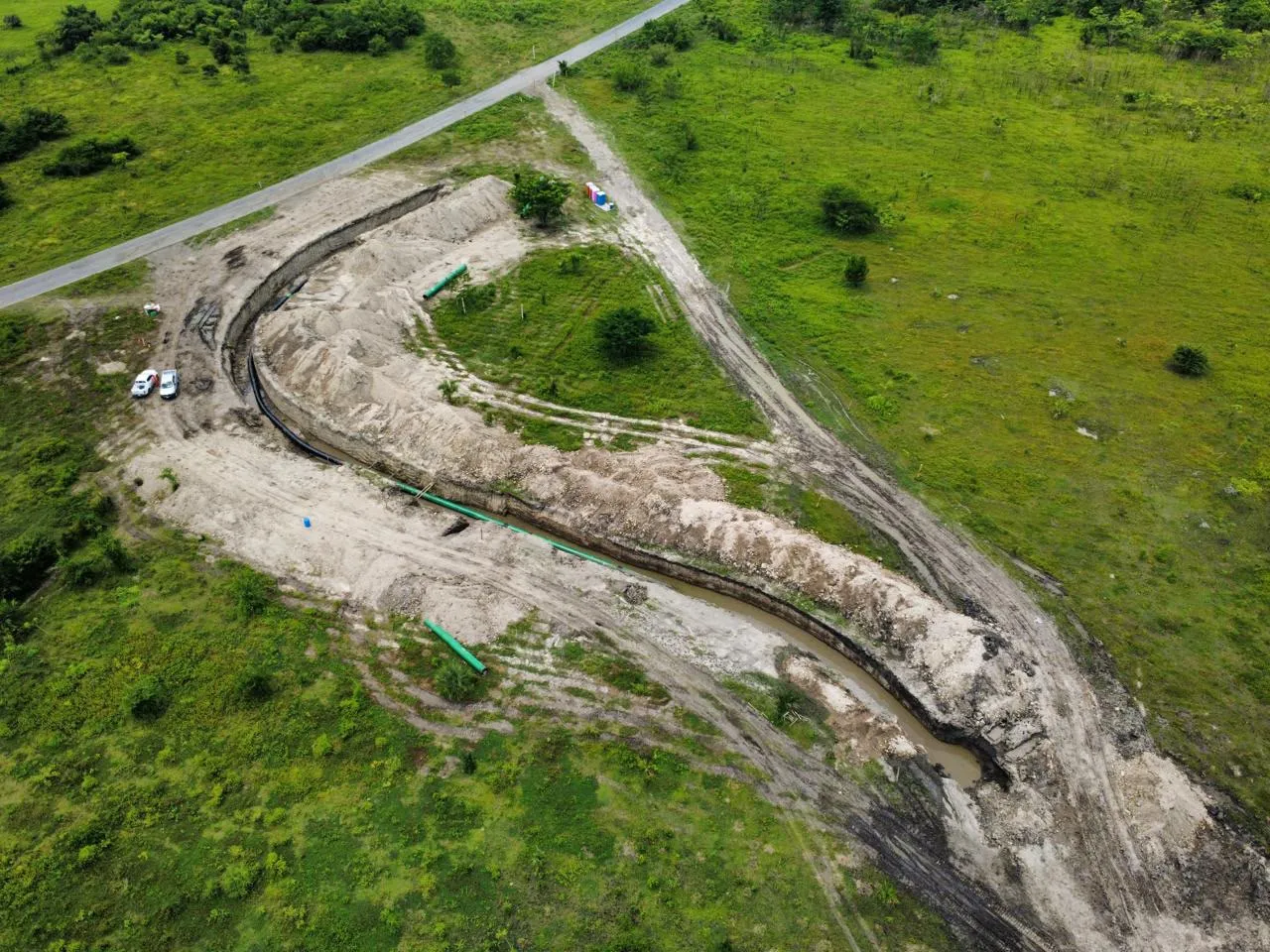 Vista aérea de zanja para tendido de tubería con vehículos de apoyo